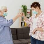 side view elder women with medical masks bumping fists salute each other scaled 1