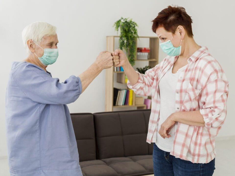 side view elder women with medical masks bumping fists salute each other scaled 1